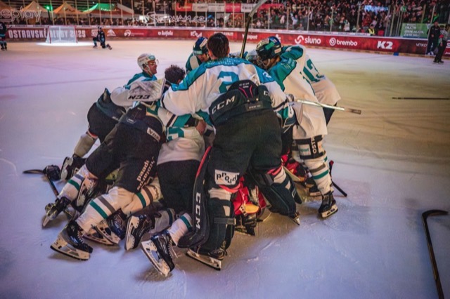 Hokejisté slaví v hromadě na ledě po konci zápasu